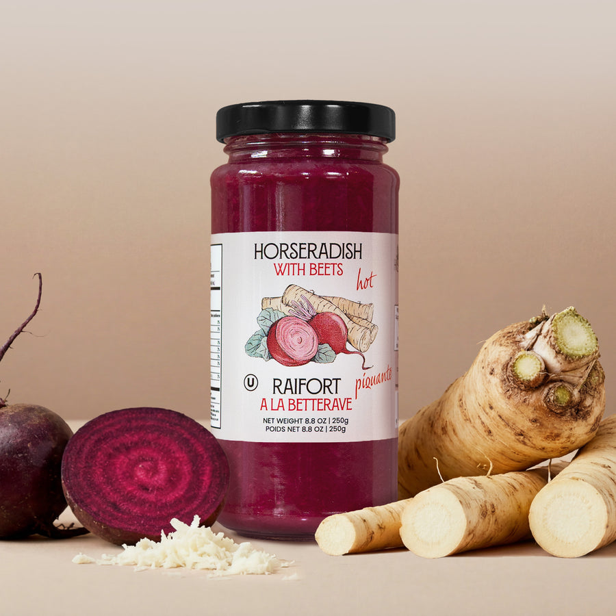 Jar of horseradish with beets , surrounded by beets and horseradish roots on a beige background.