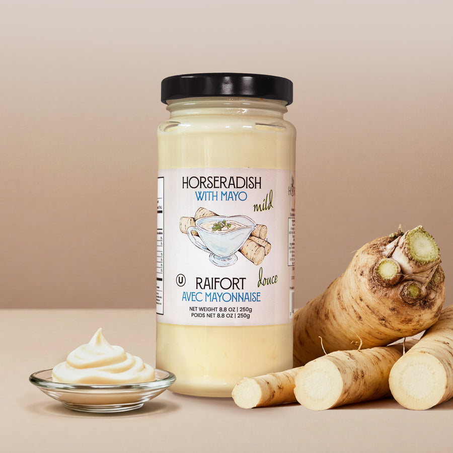 Jar of horseradish with mayo, horseradish root, and a small bowl of mayo on a beige background