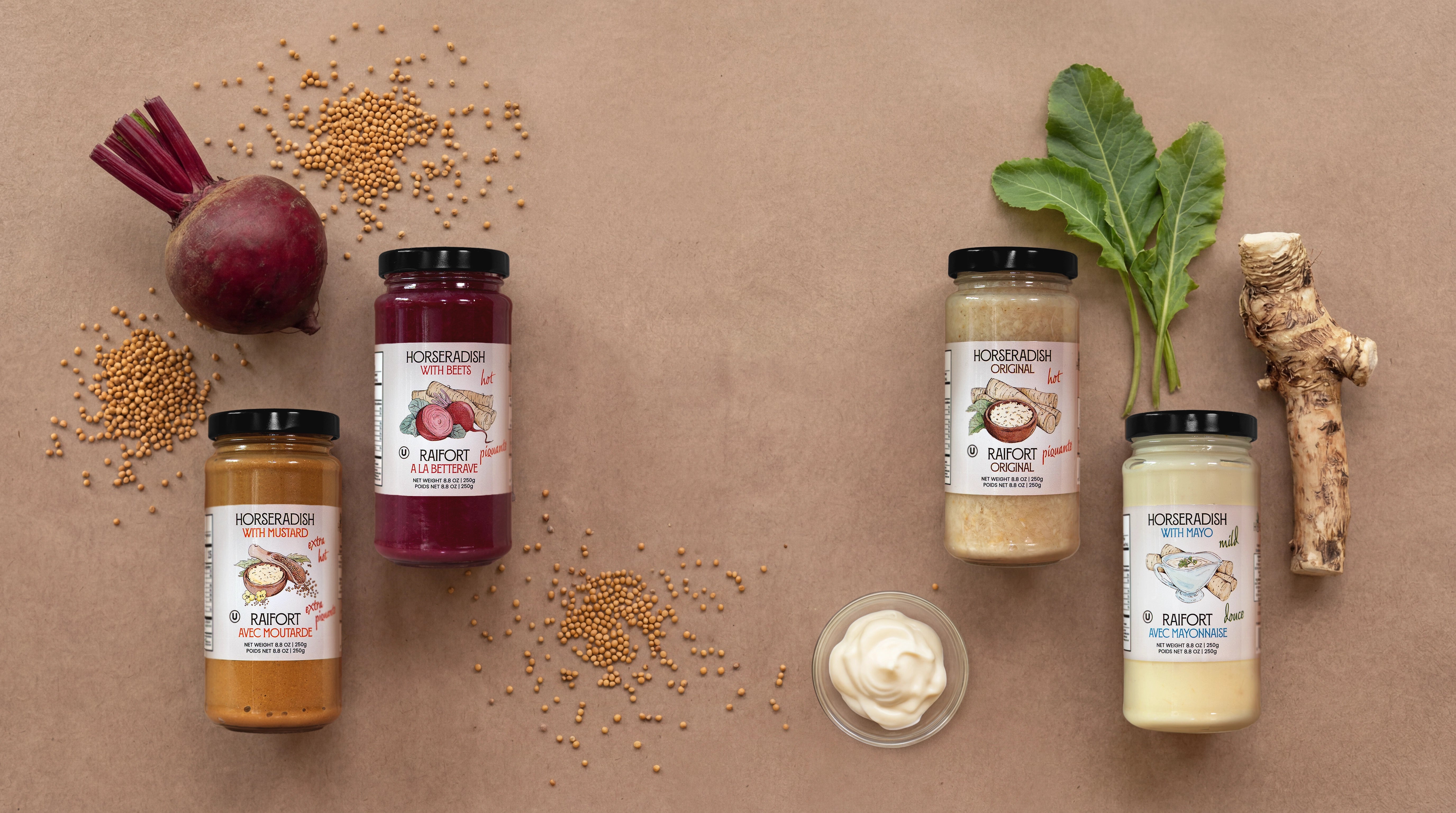 Four jars of Horseradish on a brown paper background with ingredients like beets and horseradish root, mayo and mustard seeds. Horseradish with beets, horseradish with mustard, horseradish with mayo, horseradish original tatste